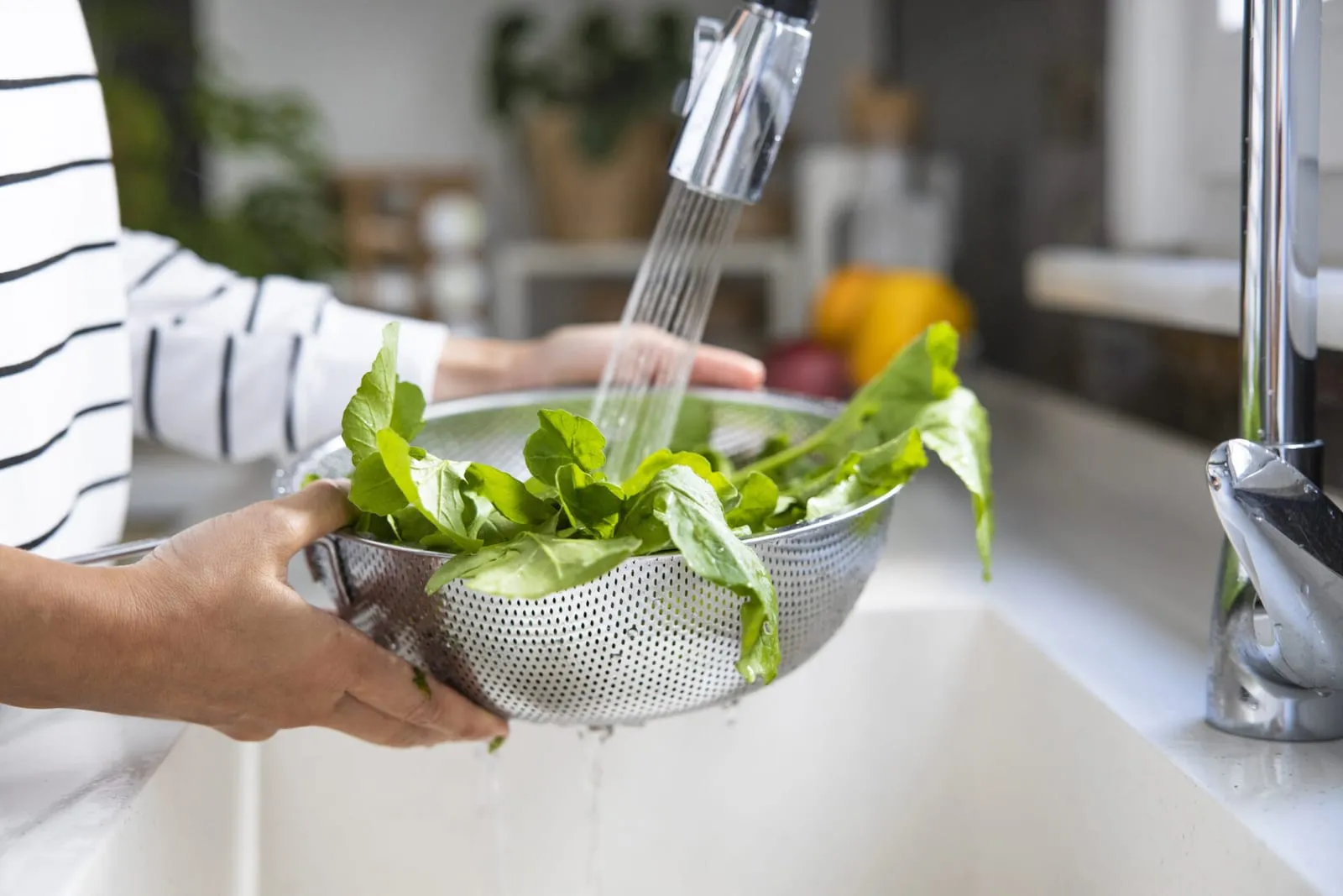 Woman washing green arugula salad