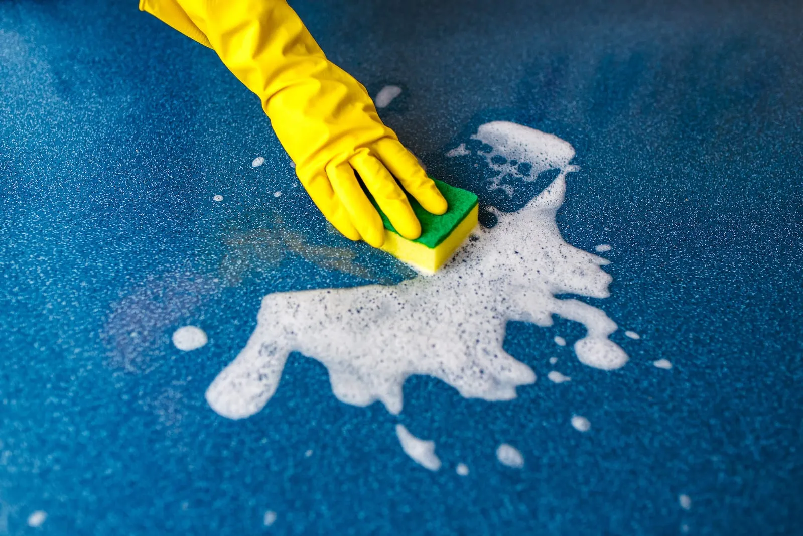 Gloved hand scrubbing a carpet