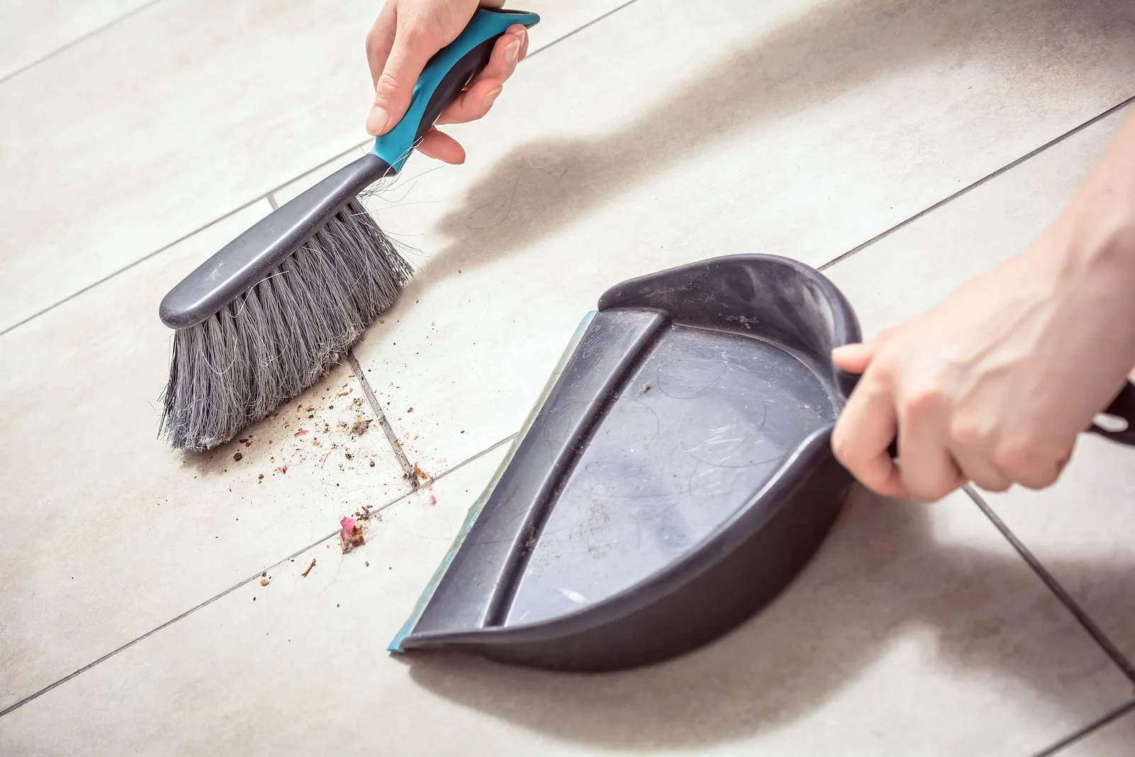 Woman sweeping stuff on tile floor