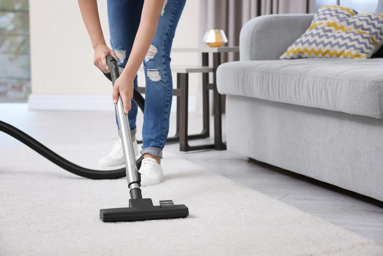 Woman using a vacuum cleaner in a lounge